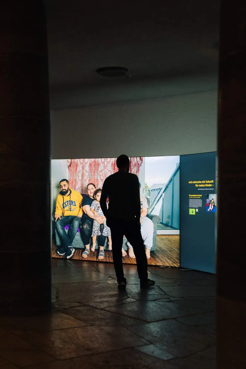 Besucher vor einem großformatigen Gruppenporträt in der Ausstellung HOME STREET HOME