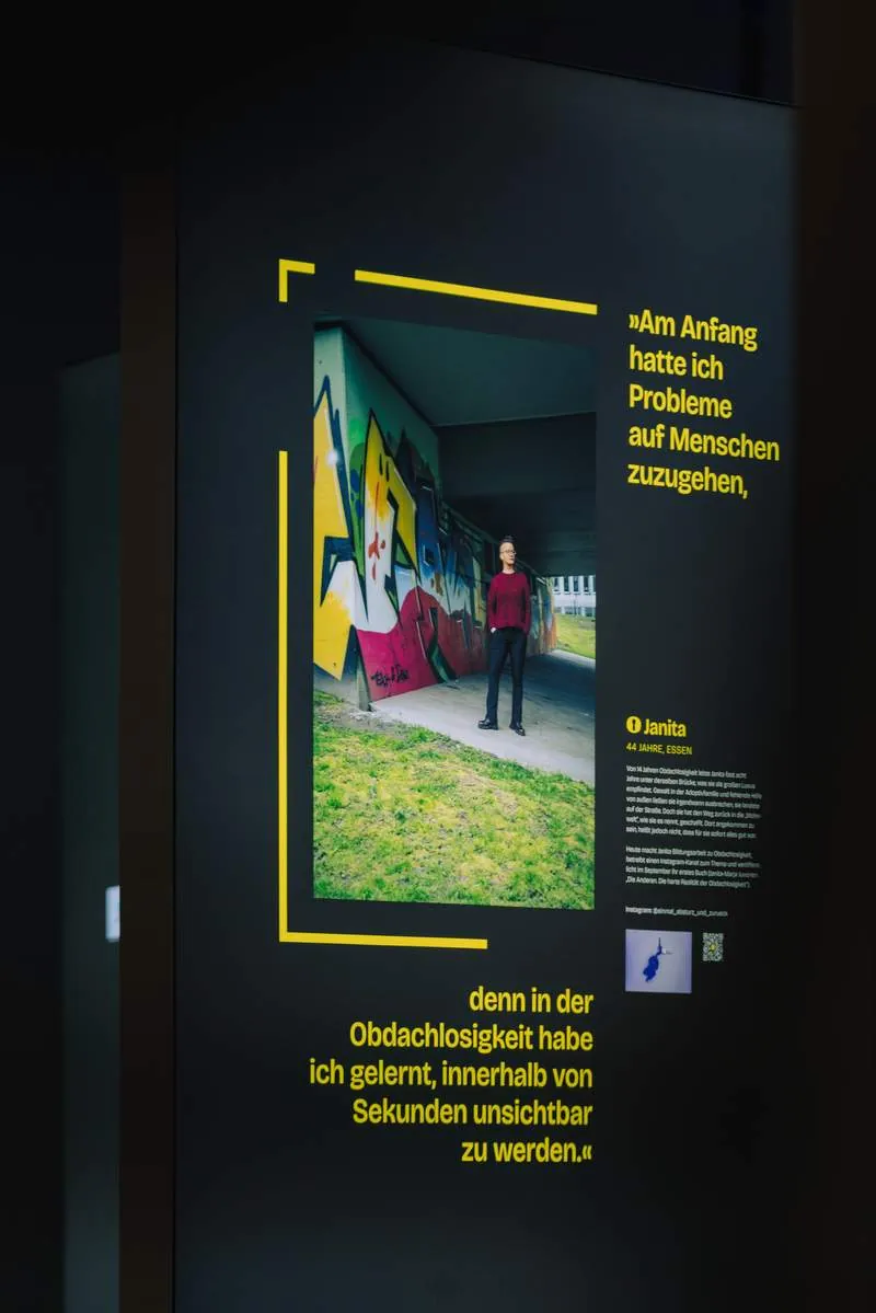 Ausstellungstafel mit Porträt und Zitat über die Erfahrung, in der Obdachlosigkeit unsichtbar zu werden