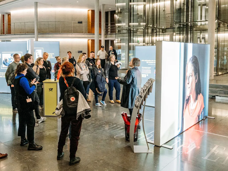 Debora Ruppert führt eine Besuchergruppe durch die Ausstellung HOME STREET HOME im Deutschen Bundestag